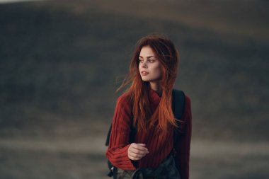 Sırt çantalı güzel bir kadın doğada çayırda yürüyor.