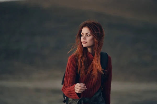 Jolie femme dans un pull avec un sac à dos marchent dans la nature dans les montagnes sur une prairie — Photo