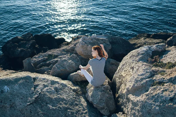 Woman in full growth sits on stones on the beach near the sea top view — Stock Photo, Image