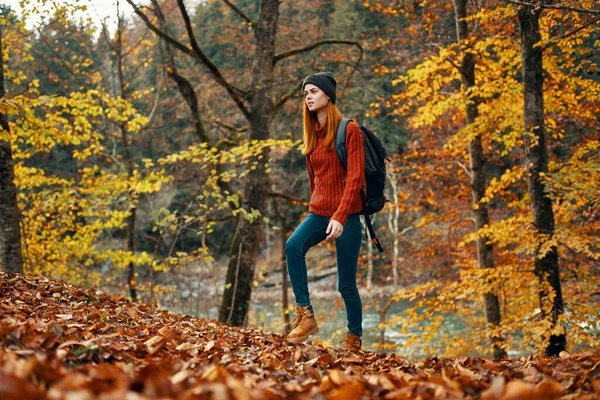 Woman tourist walks through the park in autumn with a backpack on her back and tall trees landscape river lake — Stock Photo, Image