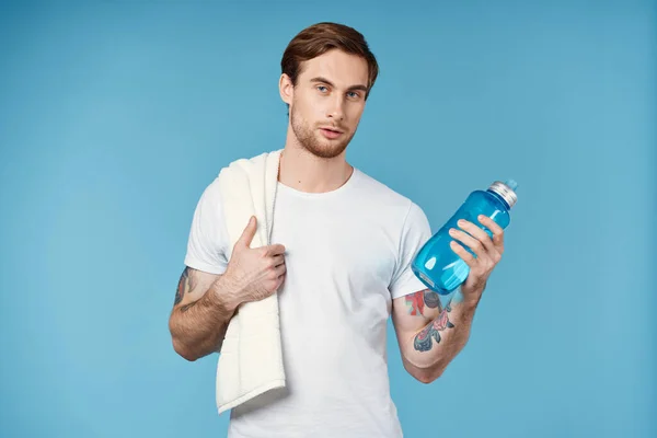 Спортсмен з татуюваннями на руках пляшка води енергія синій фон — стокове фото
