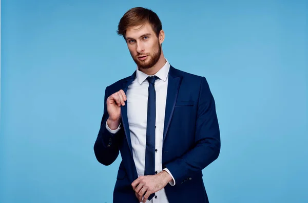 Pohledný muž v obleku sebevědomí oficiální modré pozadí — Stock fotografie
