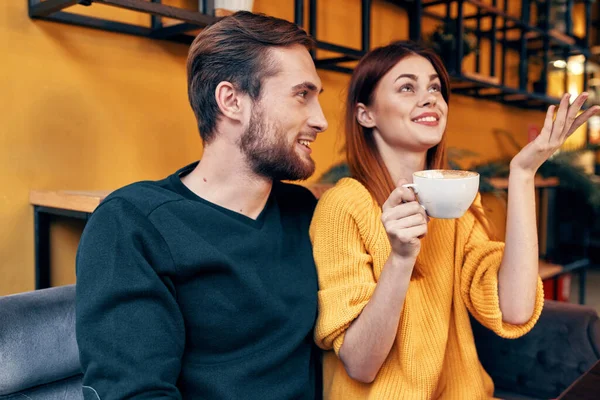 Uma mulher apaixonada por uma xícara de café e um homem feliz em uma mesa em um café comunicação amigos interiores — Fotografia de Stock
