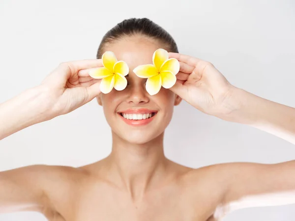 Mujer alegre con hombros desnudos flores amarillas cerca de los ojos de cerca — Foto de Stock