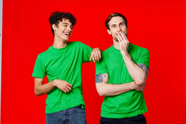 Due amici allegri in t-shirt verdi sono in piedi uno accanto all'altro — Foto Stock