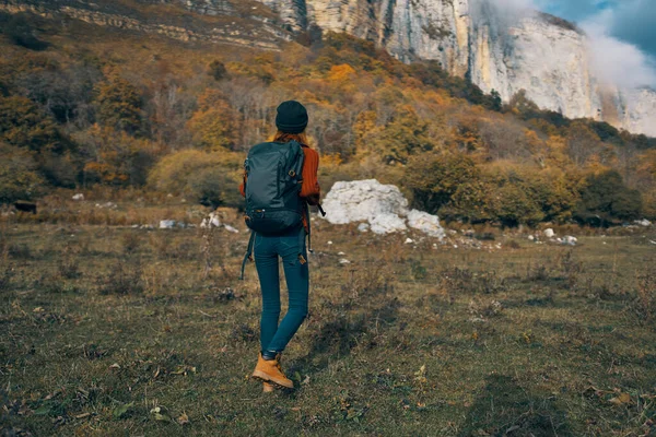 Frau in Jeansstiefeln und Pullover mit Rucksack ruhen sich im Herbst in den Bergen in der Natur aus — Stockfoto
