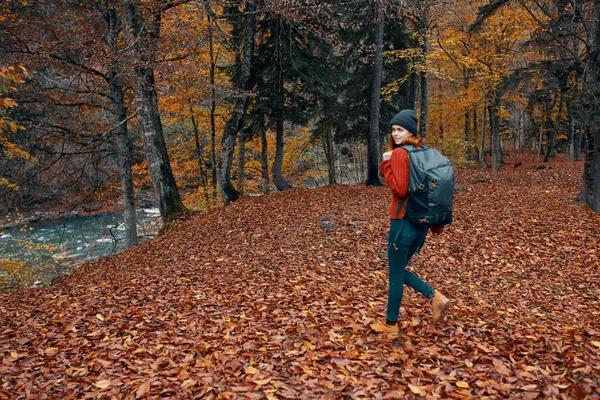 Un voyageur complet avec un sac à dos marche dans le parc avec des feuilles tombées près de la rivière — Photo