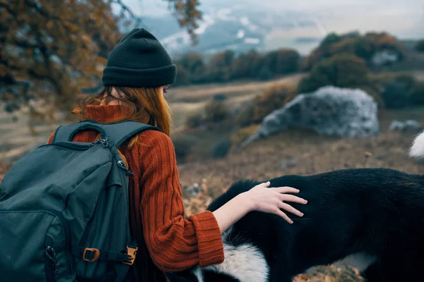 woman tourist with a backpack with a dog in nature Friendship of the city