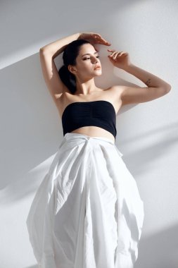 Aydınlık arka planda şık giyinmiş bir kadın portresi ve düşen bir gölge.