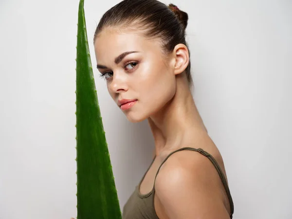 Mulher com folha verde em um fundo claro e modelo de pele limpa — Fotografia de Stock