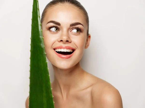Mulher feliz sorrindo e segurando folha de aloés verde na mão divertido modelo de emoção — Fotografia de Stock