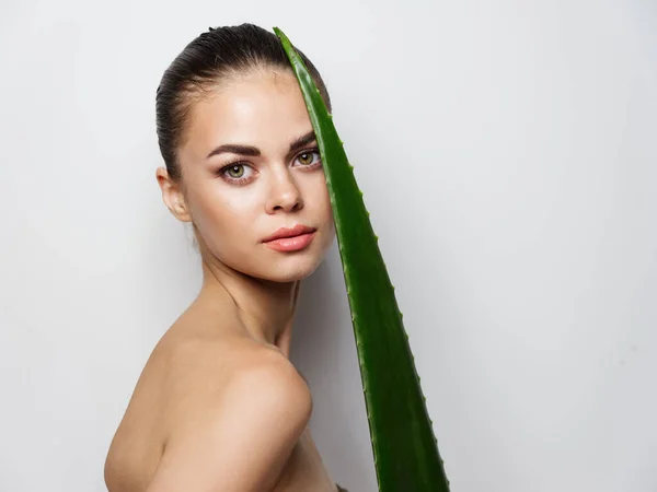 Mulher com folha de aloés verde no fundo claro vista cortada ombros nus pele limpa — Fotografia de Stock