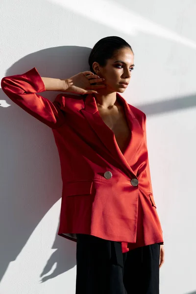 Mulher elegante em uma jaqueta vermelha está encostado contra a parede na sala e gesticulando com as mãos — Fotografia de Stock
