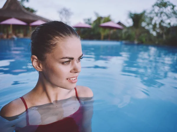 Bella donna in costume da bagno rosso con i capelli bagnati guardare di lato e nuota in piscina in natura — Foto Stock