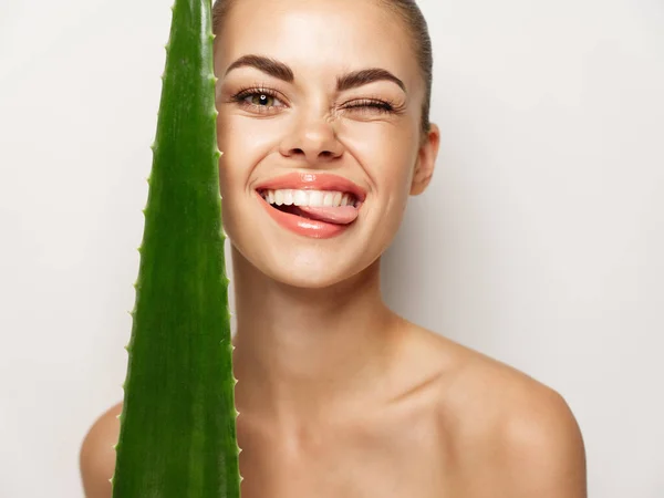 Mulher alegre com folha de aloé mostra sua língua e ri em um fundo leve — Fotografia de Stock