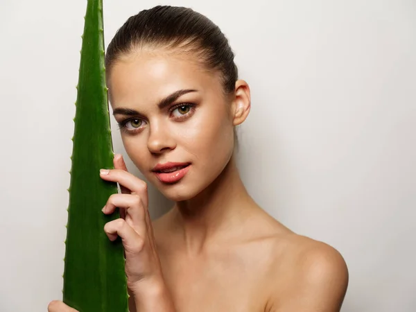 Bela mulher abraça uma folha de aloés verde com as mãos — Fotografia de Stock