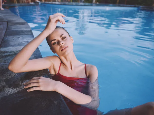 Mulher sexy em maiô vermelho apoiando-se na telha e água clara na piscina — Fotografia de Stock