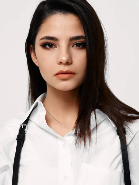 Beautiful brunette with makeup on her face and white shirt with suspenders — Stock fotografie