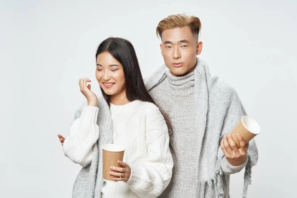Happy man and woman of asian appearance with cups of coffee and warm clothes — Stock fotografie