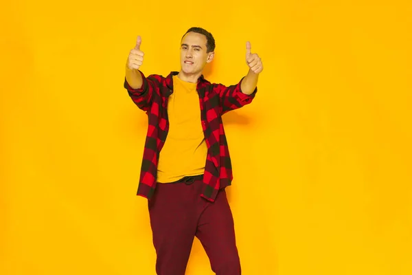 Wesoły mężczyzna w koszuli w kratę gestykulujący dłońmi żółtym tłem — Zdjęcie stockowe