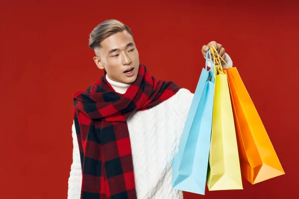 Man of asian appearance winter clothes bags in hands gifts — Photo