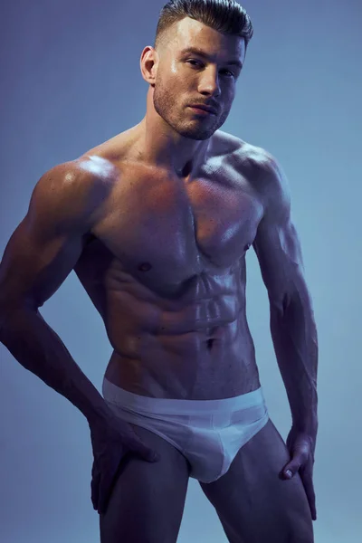 Homem desportivo com corpo bombeado em calcinha branca posando fisiculturista — Fotografia de Stock