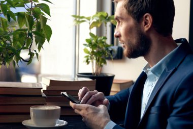 Takım elbiseli bir iş adamı bir kafede kahvaltı masasında oturuyor.