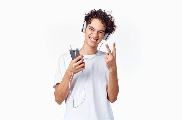 Man met krullend haar en koptelefoon wit t-shirt licht achtergrond close-up bijgesneden — Stockfoto