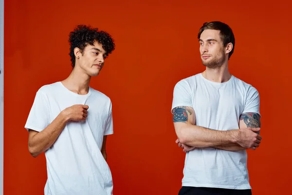 Чоловіки в білих футболках спілкування дружба червоний фон — стокове фото