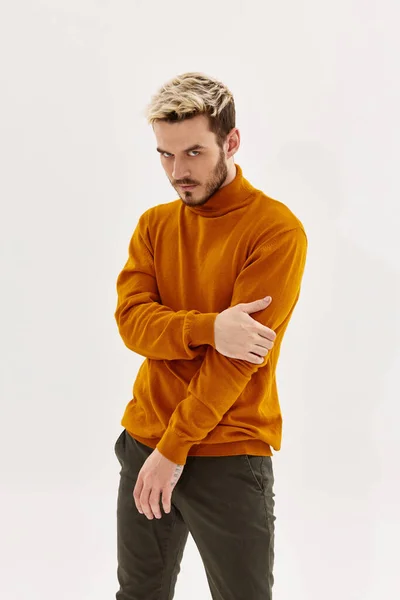 Stylish man in orange sweater touches his hand and looks down — Stock Photo, Image