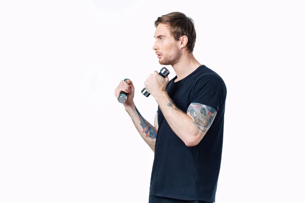 Αθλητής σε μαύρο t-shirt ασχολούνται με τη φυσική κατάσταση σε λευκό φόντο σε εσωτερικούς χώρους και αλτήρες στο χέρι — Φωτογραφία Αρχείου