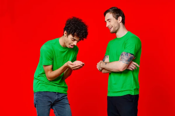 Twee man groene t-shirts omarmen emoties vriendschap rode achtergrond — Stockfoto