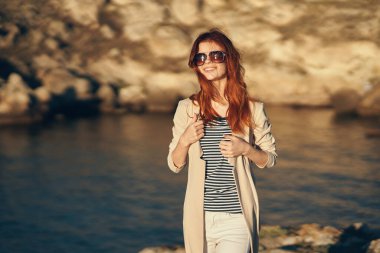 Kadın dağlarda seyahat ediyor. Yaz gözlükleriyle nehir kenarındaki turizm modeli.