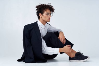 Klasik takım elbiseli kıvırcık saçlı, stüdyo fotoğrafçısı spor ayakkabılı adam.