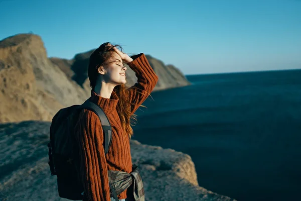 Hübsche Frau im Pullover mit Rucksack am Meer in der Natur — Stockfoto