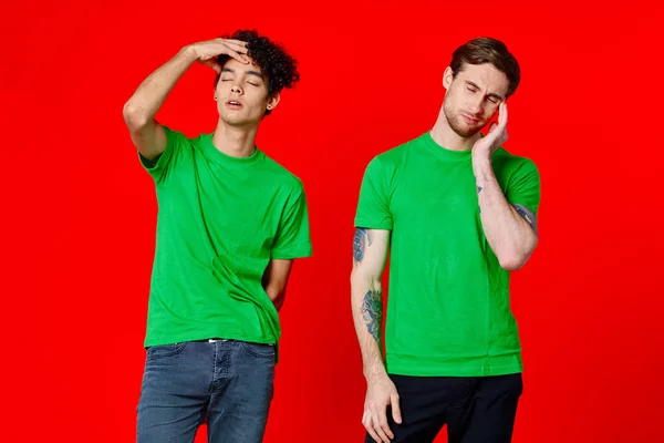 Due amici in t-shirt verdi sono in piedi accanto a stagno con le mani emozioni sfondo rosso — Foto Stock