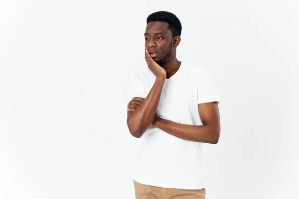 Man aanraken gezicht met de hand afrikaanse verschijning model wit t-shirt puzzled look — Stockfoto