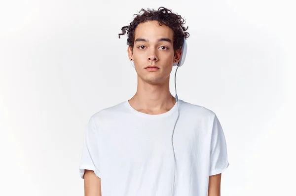 Adolescente em uma camiseta ouvindo música em fones de ouvido em um fundo leve vista cortada — Fotografia de Stock