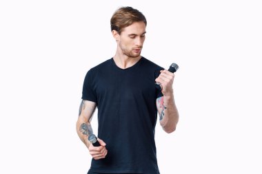 Elinde dambıllar olan erkek sporcu arka planda hafif bir kesim manzarası var.