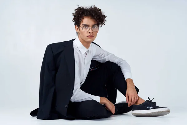 Homem elegante com cabelo encaracolado em tênis em um fundo leve uma jaqueta no modelo de calças de ombro — Fotografia de Stock