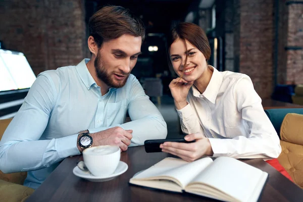 Uomo e donna d'affari seduti in un caffè con un telefono di comunicazione di riposo snack in mano — Foto Stock