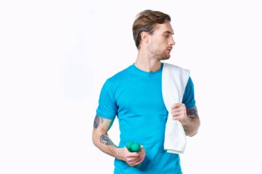 Elinde dambıllar olan bir adam omuzlarında havlu spor salonu ışık arka planında.