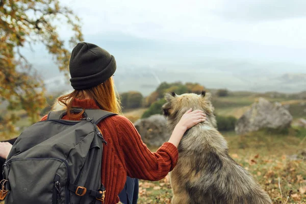 Žena turista objetí pes v přírodě obdivuje krajinu — Stock fotografie