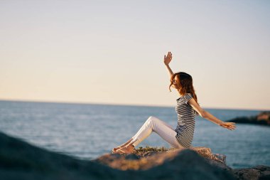 Deniz kenarındaki dağlarda mutlu bir gezgin. El kol hareketi yapıyor. Tatil modeli.