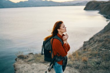 Sırt çantalı bir gezgin açık havada, deniz manzaralı dağlarda. Boşluğu kopyala.