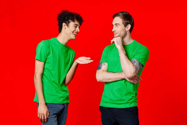 녹색 티셔츠를 입은 두 남자가 나란 히서 서 의사소통을 하고 있다 — 스톡 사진