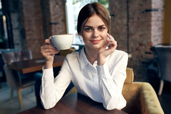 커피를 마시며 테이블에 앉아 있는 여성 — 스톡 사진