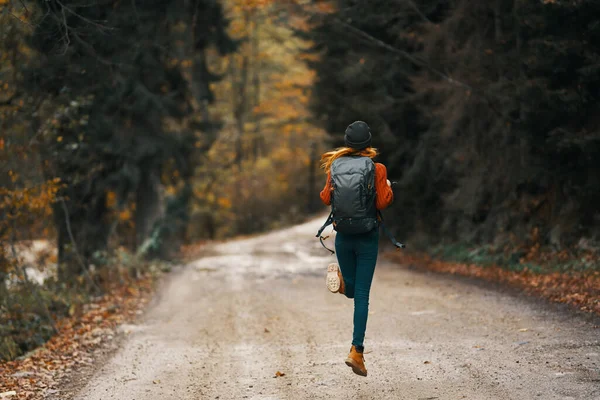 Viajante feliz com mochila caminha na estrada na floresta de outono — Fotografia de Stock