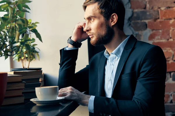 Homme d'affaires en costume assis à une table avec une tasse de café dans un café repos — Photo