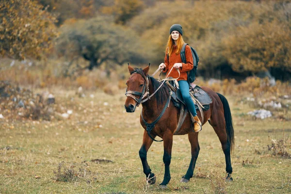 Woman hiker rides a horse in a field mountains nature landscape — Stock Photo, Image